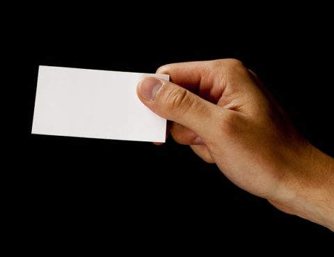 A person holding a white card in their hand.