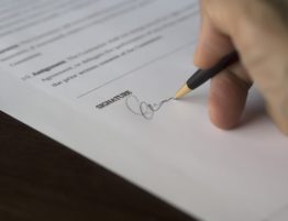A person signing a document with a pen.